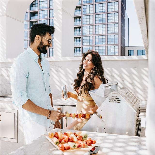 A man and a woman preparing food on a grill