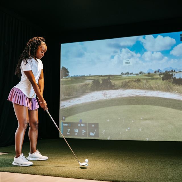 A woman playing a golf game simulation